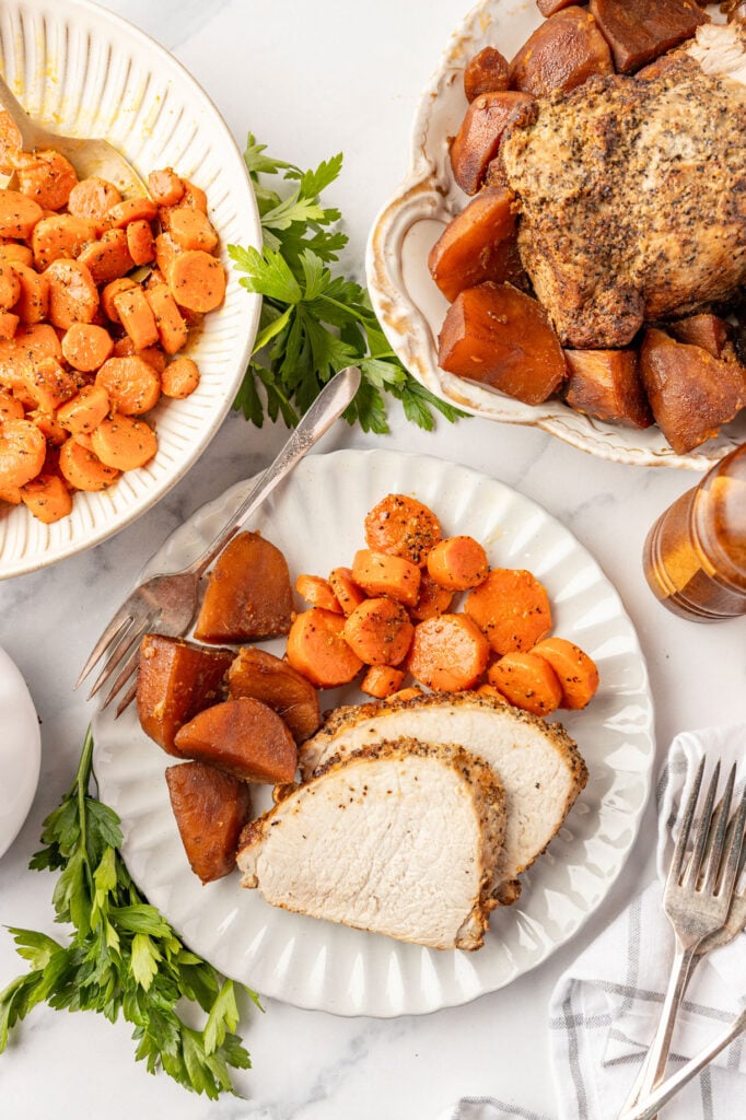 Plate of sliced Roasted Pork Loin with brown potatoes, carrots, and gravy, ready to serve.