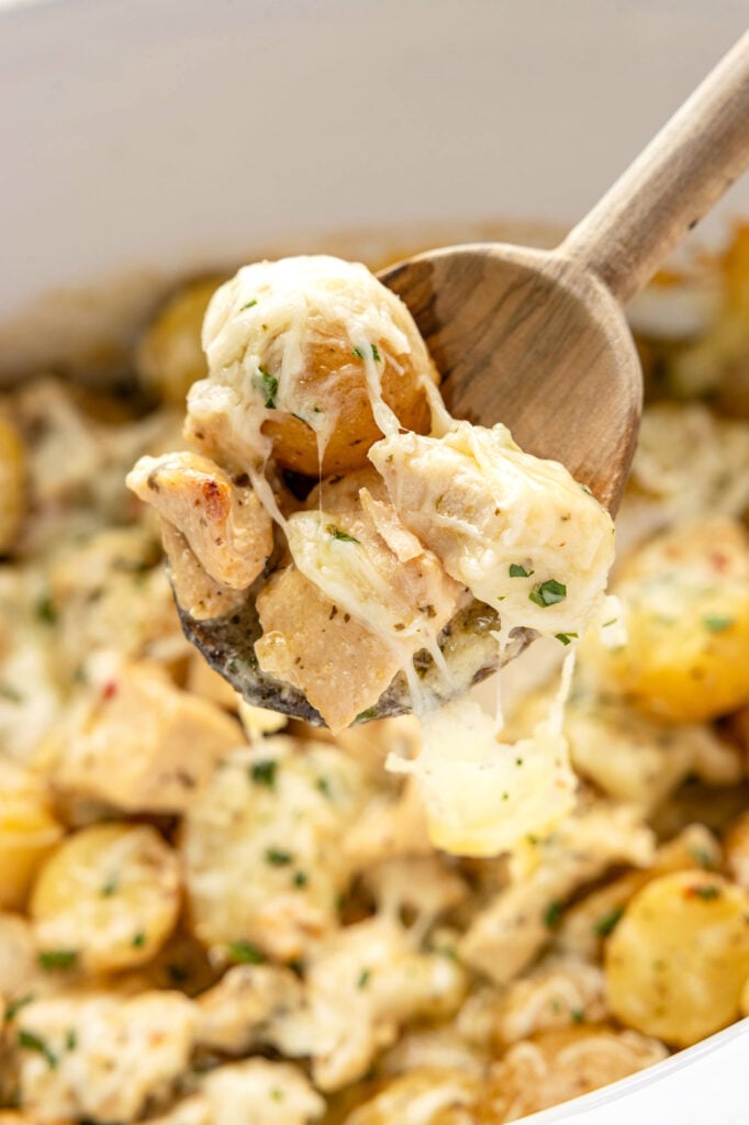 spoon scooping up Slow Cooker Garlic Parmesan Chicken And Potatoes from a slow cooker