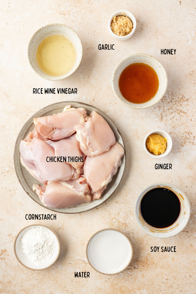 Overhead view of ingredients for Slow Cooker Teriyaki Chicken, including chicken thighs, soy sauce, honey, ginger, and garlic.