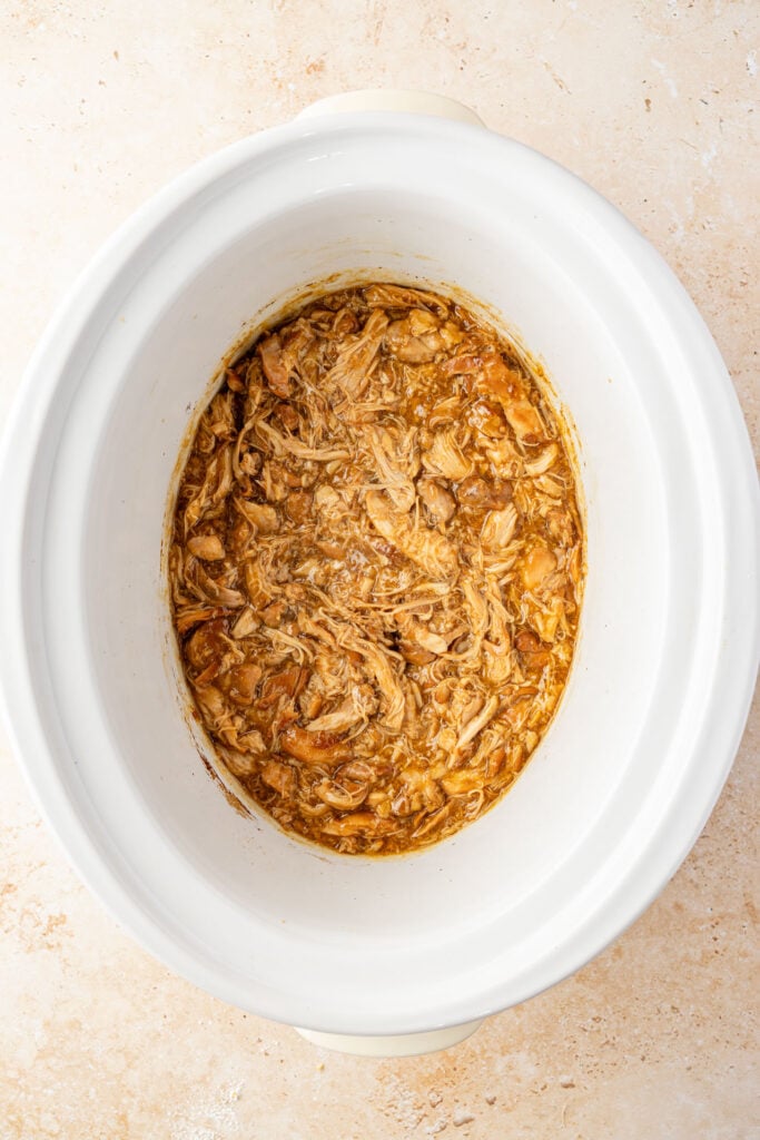 Overhead view of cooked Slow Cooker Teriyaki Chicken in a white crockpot.